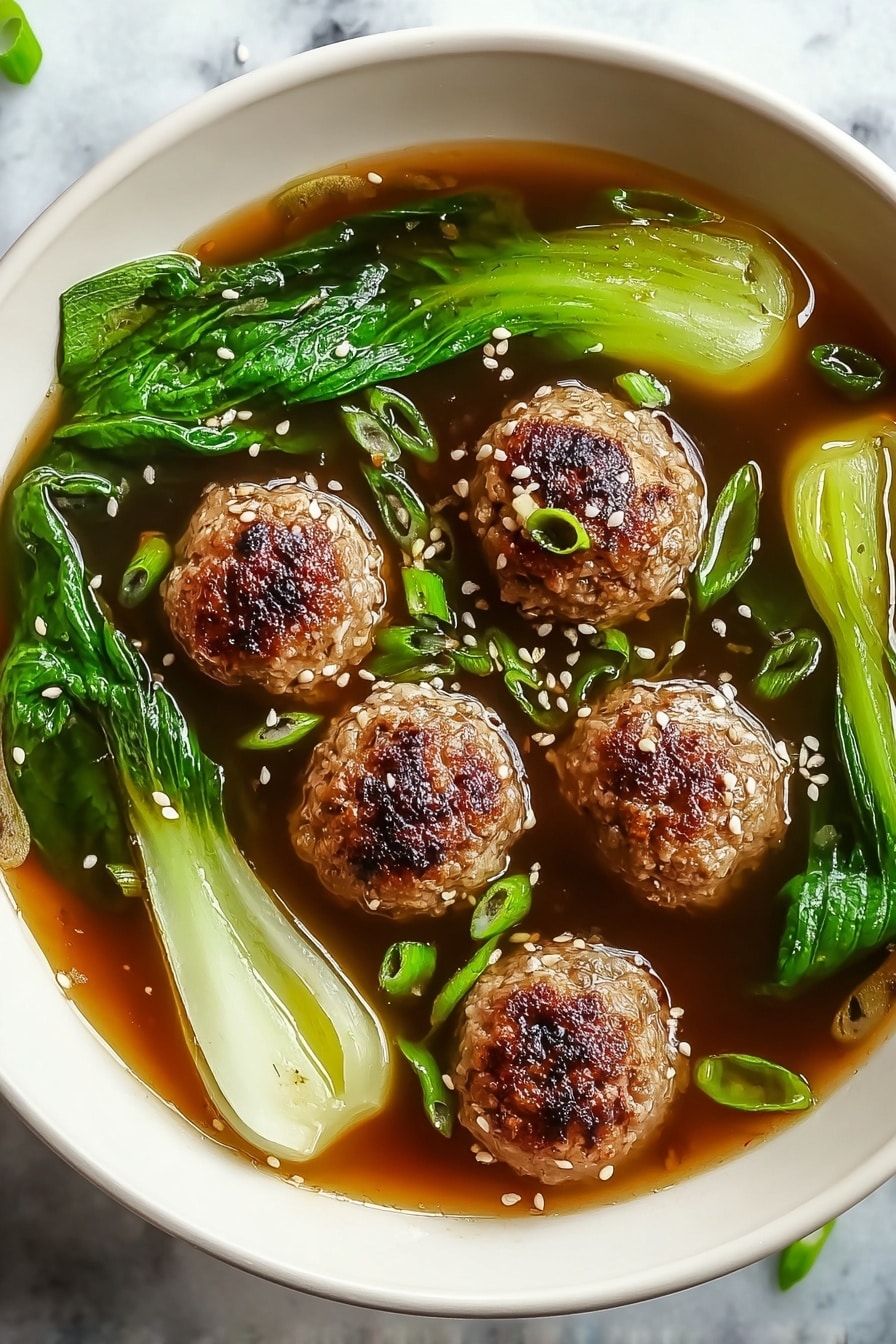 A white bowl filled with a clear brown broth containing six browned meatballs with a slightly crispy top, arranged evenly in the center. Surrounding the meatballs are bright green bok choy leaves with white stalks, partially submerged in the broth. Sprinkled on top and floating in the broth are small green onion pieces and white sesame seeds, adding texture and color contrast. The bowl is set on a white marbled surface. photo taken with an iphone --ar 2:3 --v 7 - Ginger Chicken Meatball Soup with Bok Choy, healthy chicken soup with ginger and bok choy, easy Asian-inspired chicken meatball soup, comforting chicken and bok choy soup, flavorful ginger chicken soup recipe